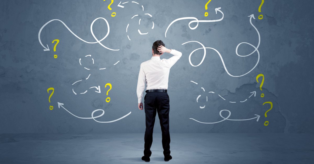 A man in business clothing standing with question marks and arrows drawn around him on a white background.