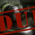 A red box with the letters "DUI" inside sits in front of a court judge's wooden gavel and sounding block.